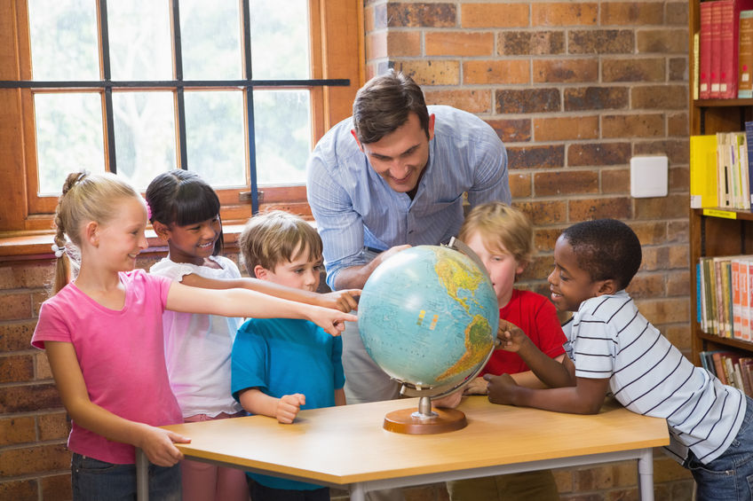 38312492 - cute pupils and teacher looking at globe in library at elementary school
